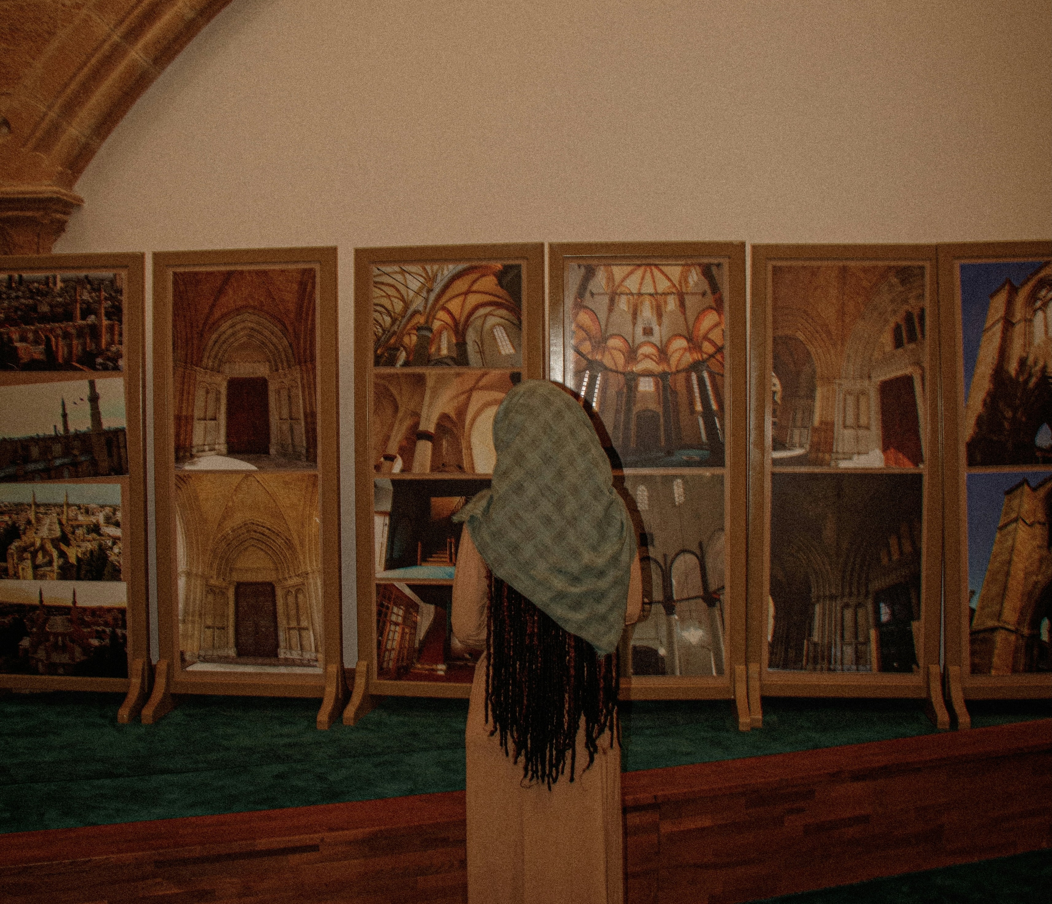 A traveler examining framed artwork inside a vaulted gallery.