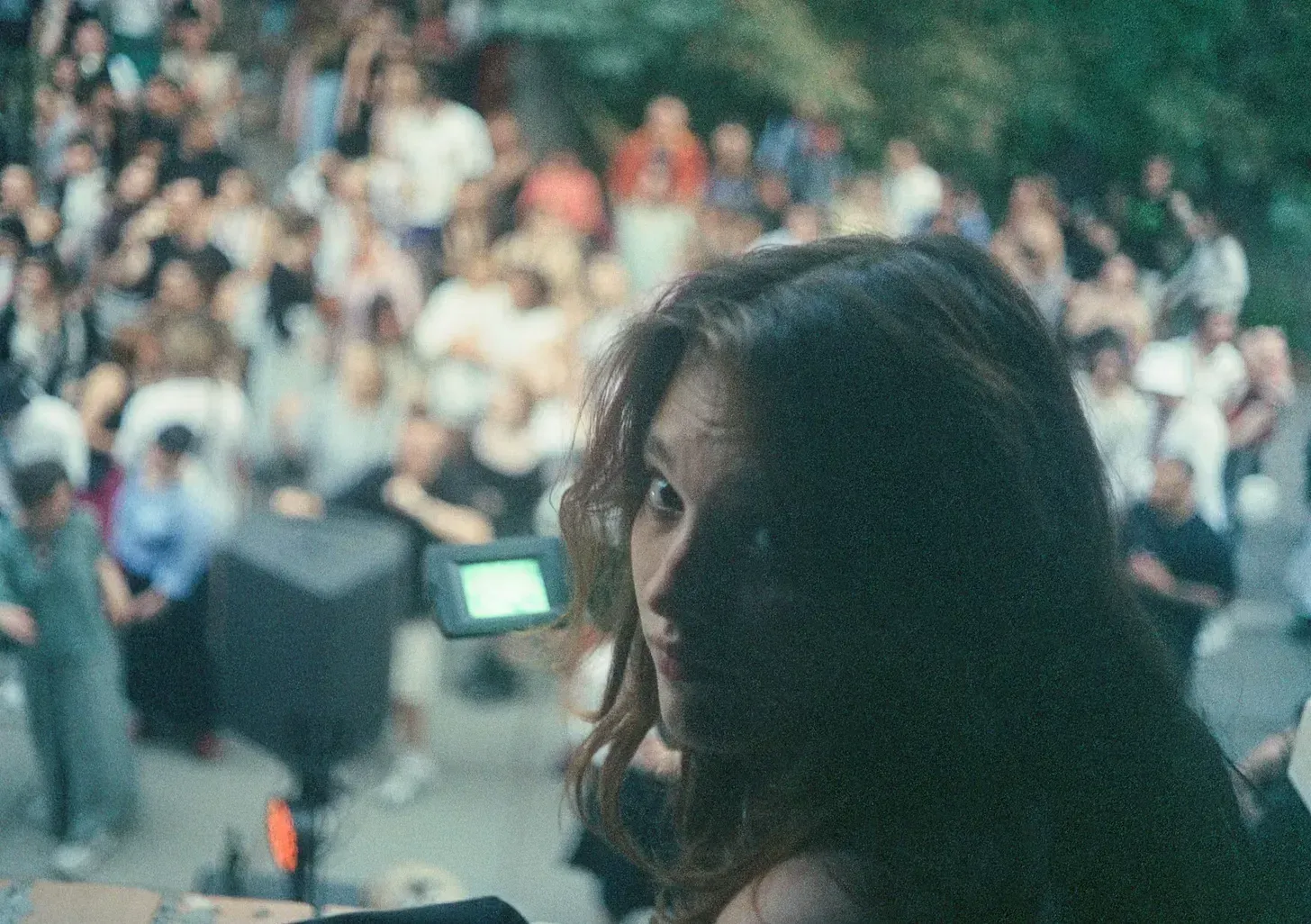 A traveler glancing back over her shoulder at an outdoor gathering.